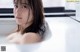A woman sitting in a bathtub with her hands on her breasts.